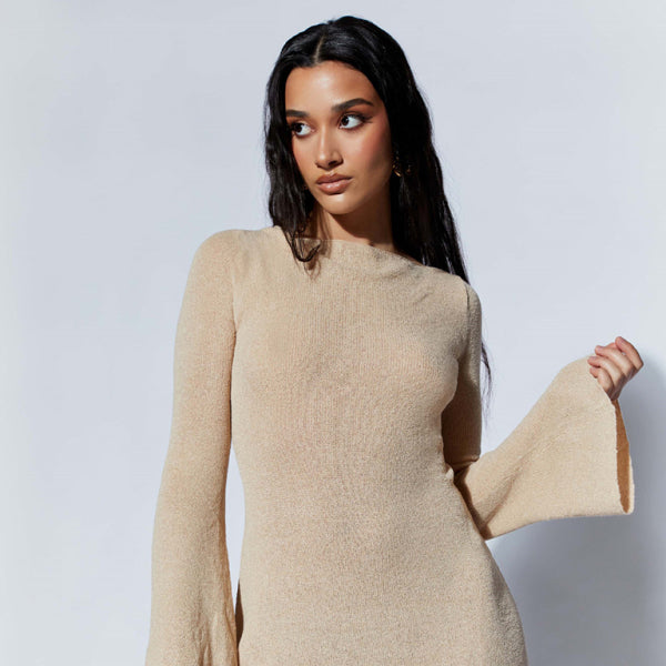 A woman wearing a beige backless knitted dress with bell sleeves and a slim fit.