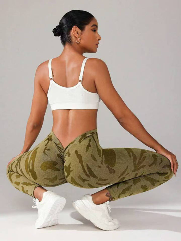 A person wearing high-waisted, camouflage seamless yoga pants, in a crouched position showcasing the leggings' fit and waistlifting effect.