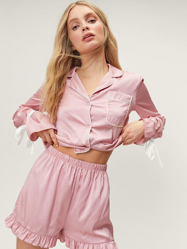 A woman wearing a pink long-sleeved pajama top with a lapel collar and matching shorts, both with ruffle details.