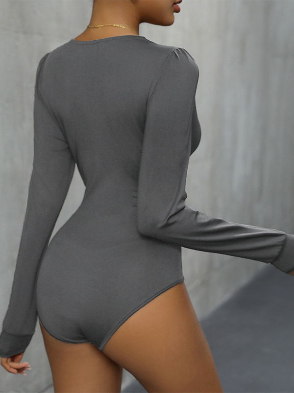 A woman wearing a gray long sleeve bodysuit with lace detailing. 